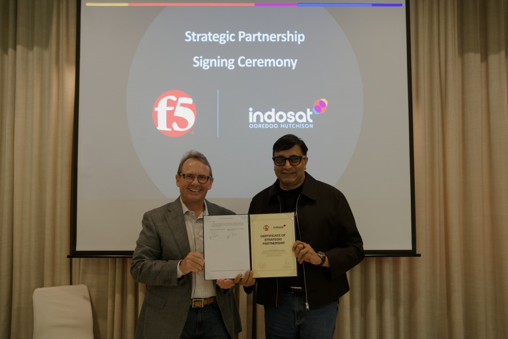 Perwakilan F5 dan Indosat memegang dokumen kemitraan strategis di depan layar